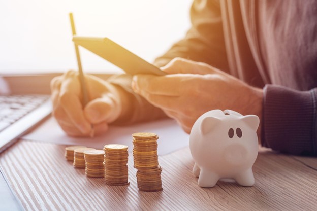 An image of a man calculating the extra money he has made from selling his non running car. The image contains coins and a man using a calculation device.