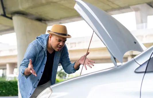 Frustrated motorist looks under the bonnet of his non-running car