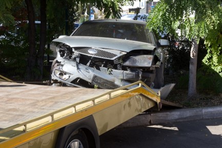 A wrecked car is loaded onto a tow truck.