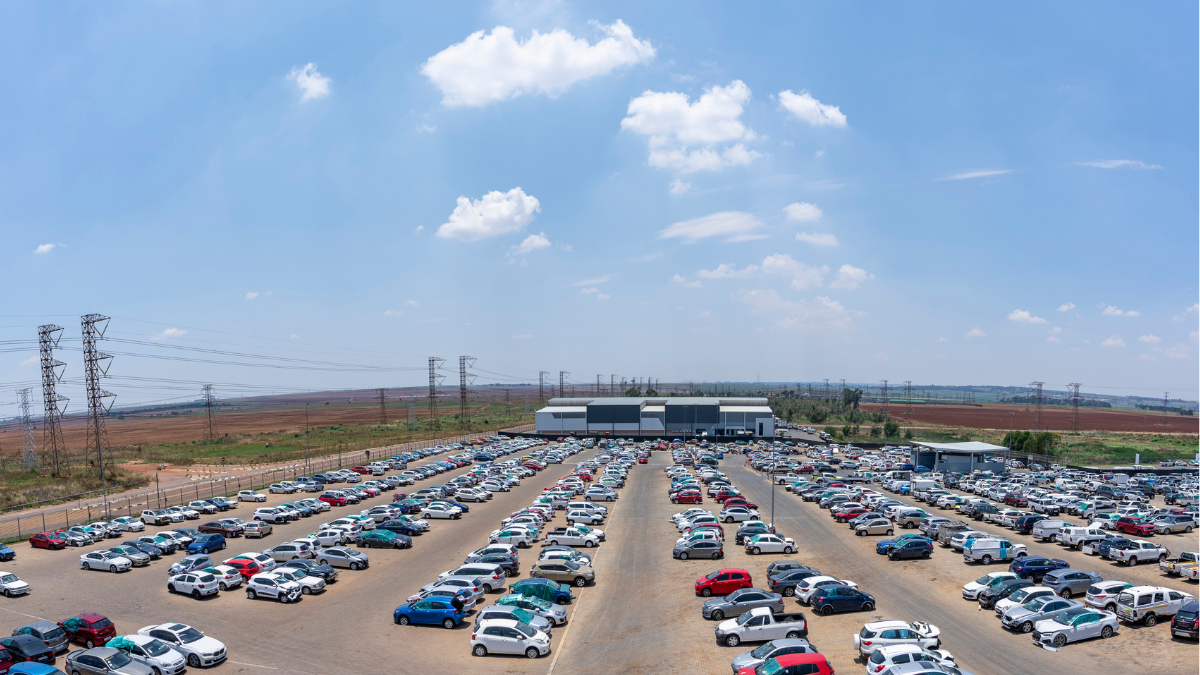 Aerial view of a large vehicle storage and salvage yard under a blue sky.