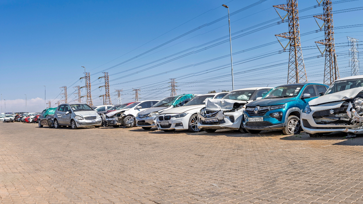 Rows of damaged and salvage vehicles parked in an outdoor storage yard.