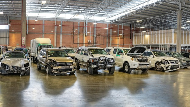 Damaged vehicles stored indoors at a professional salvage facility.